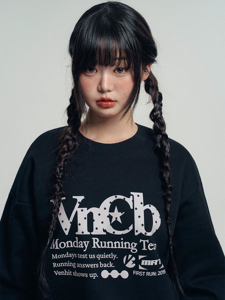 Woman with black hair in braids and bangs wearing a black sweatshirt