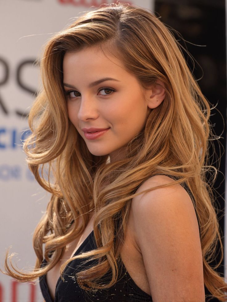 Woman with long wavy blonde hair wearing a black top, looking at the camera