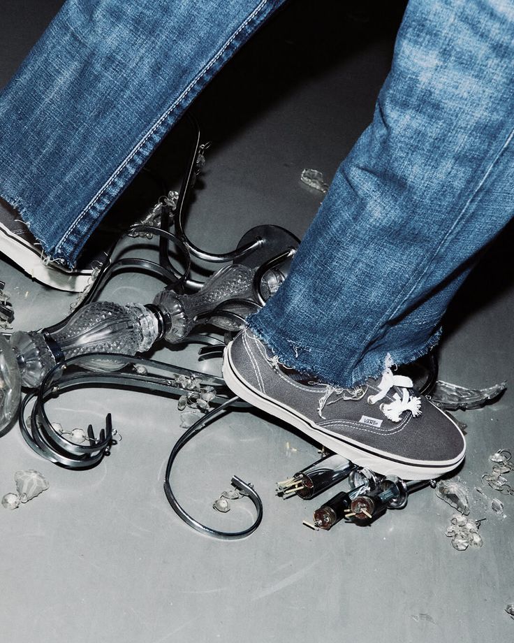 Person in blue jeans and sneakers stepping on a broken chandelier