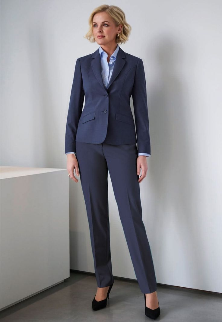 Woman in a navy blue suit and light blue shirt standing indoors