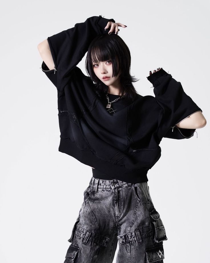 Person with black shaggy hair wearing a black sweatshirt and cargo pants