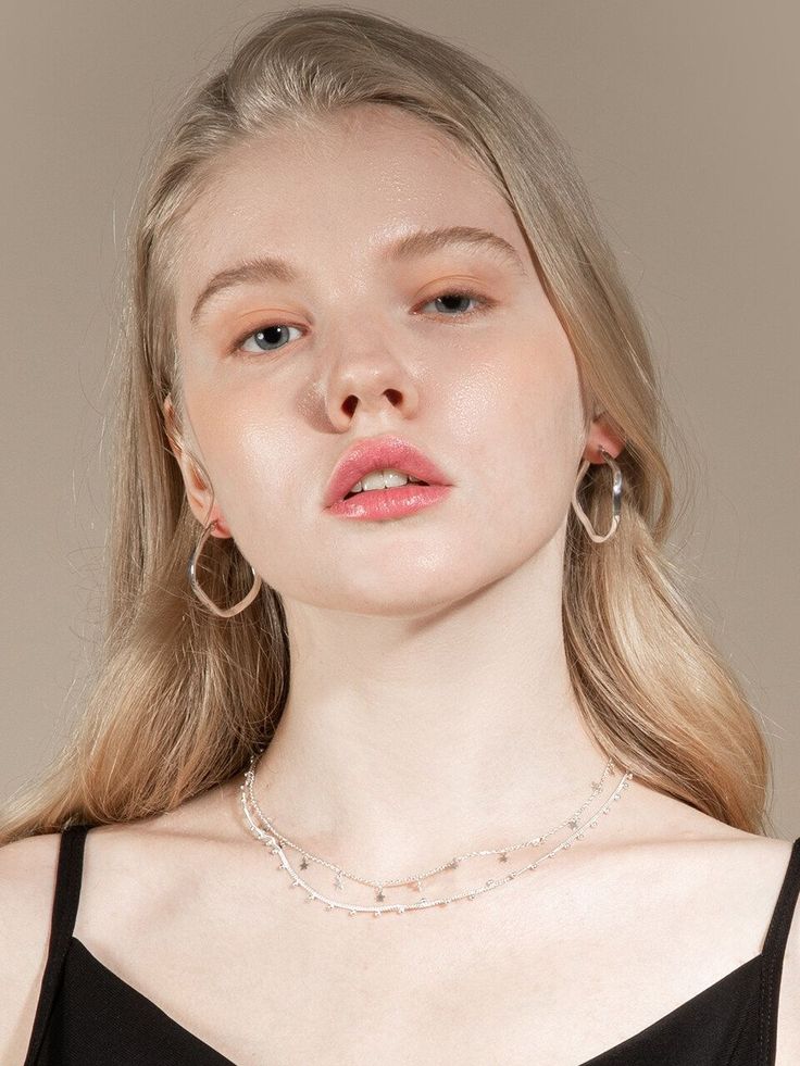 Woman with blonde hair wearing hoop earrings and a layered necklace