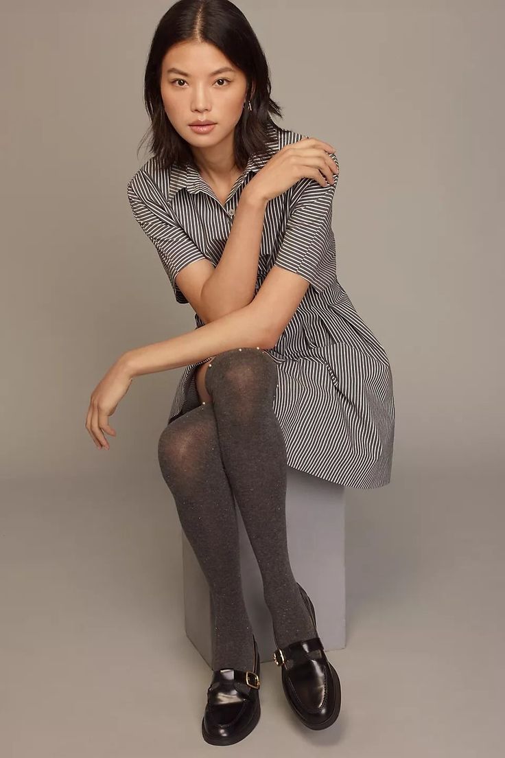 Woman in a striped dress and knee-high socks sitting in a studio