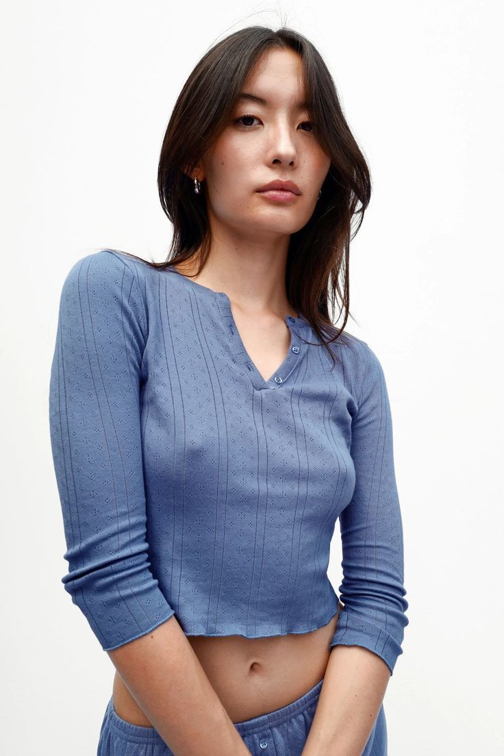 Woman in a blue long-sleeve top and matching bottoms with exposed midriff