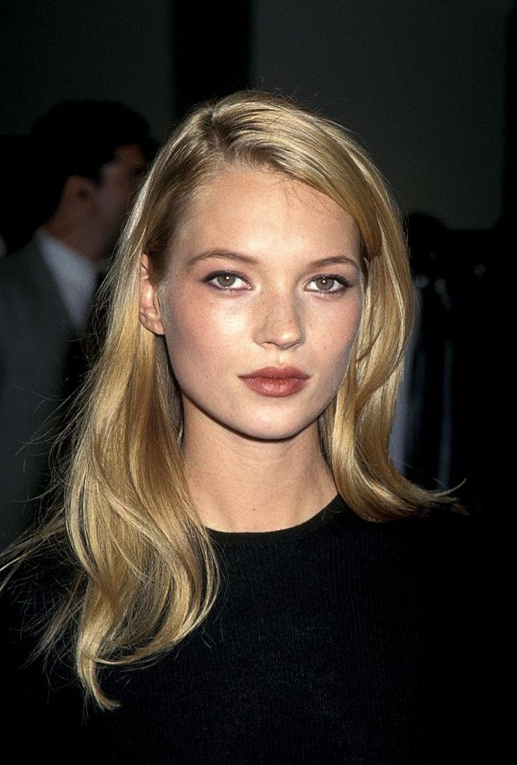 Woman with blonde hair wearing a black top, captured in a soft-lit portrait