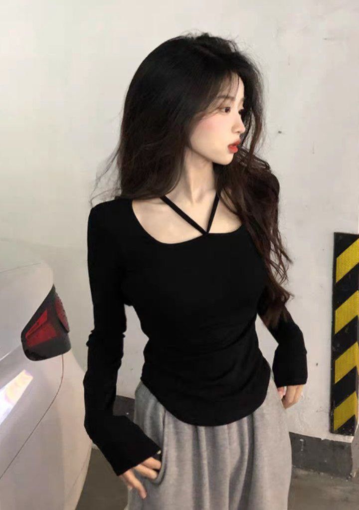 Woman with long dark hair wearing a black top and grey sweatpants indoors