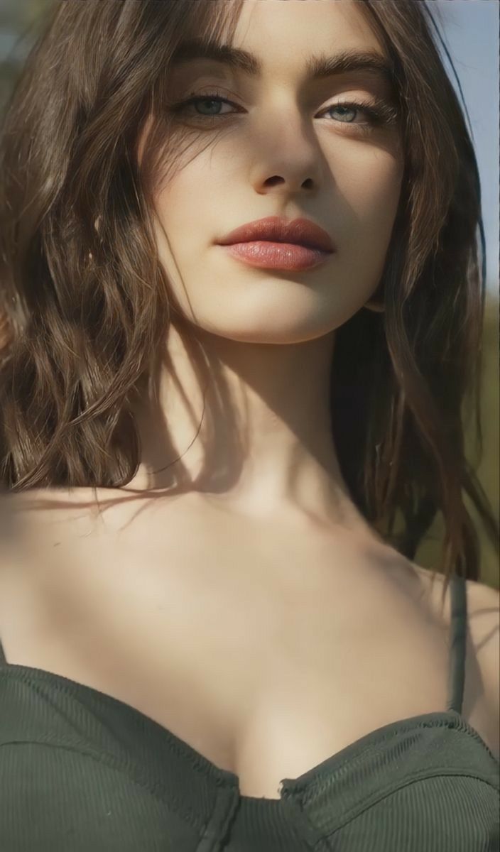 Woman with long hair and green eyes in soft lighting, upper body portrait