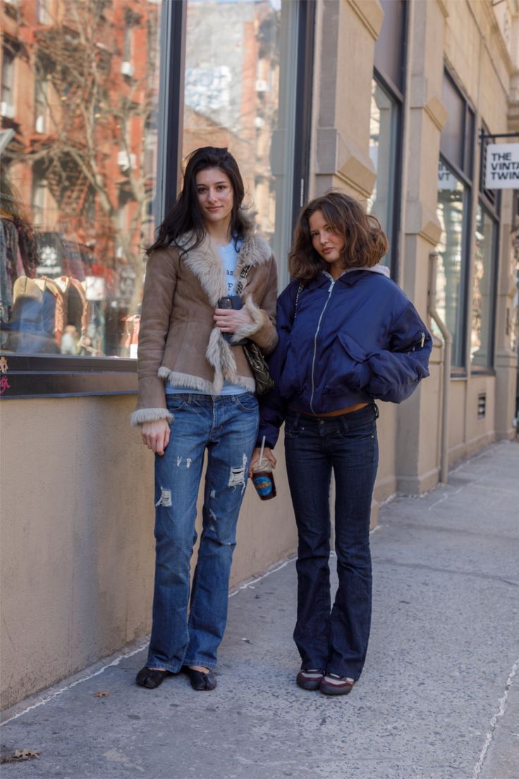 Two women standing on a city street in front of a store window