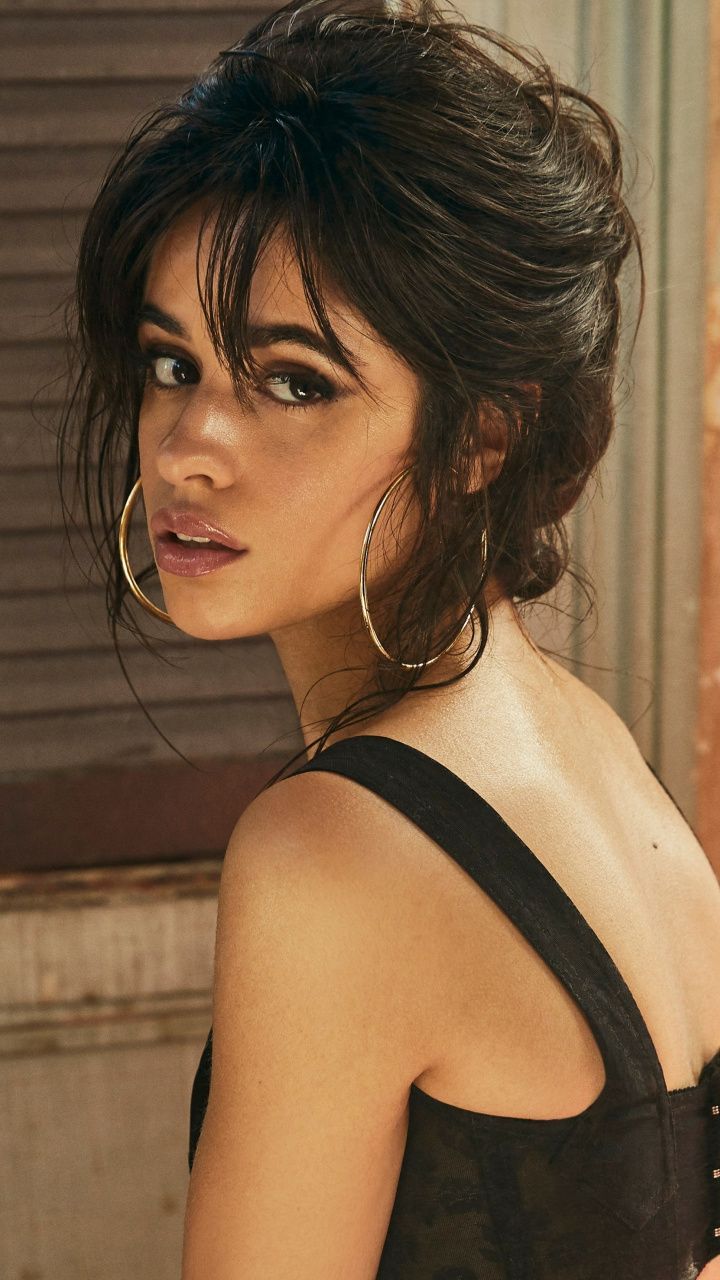 Woman with dark hair and hoop earrings looking over her shoulder