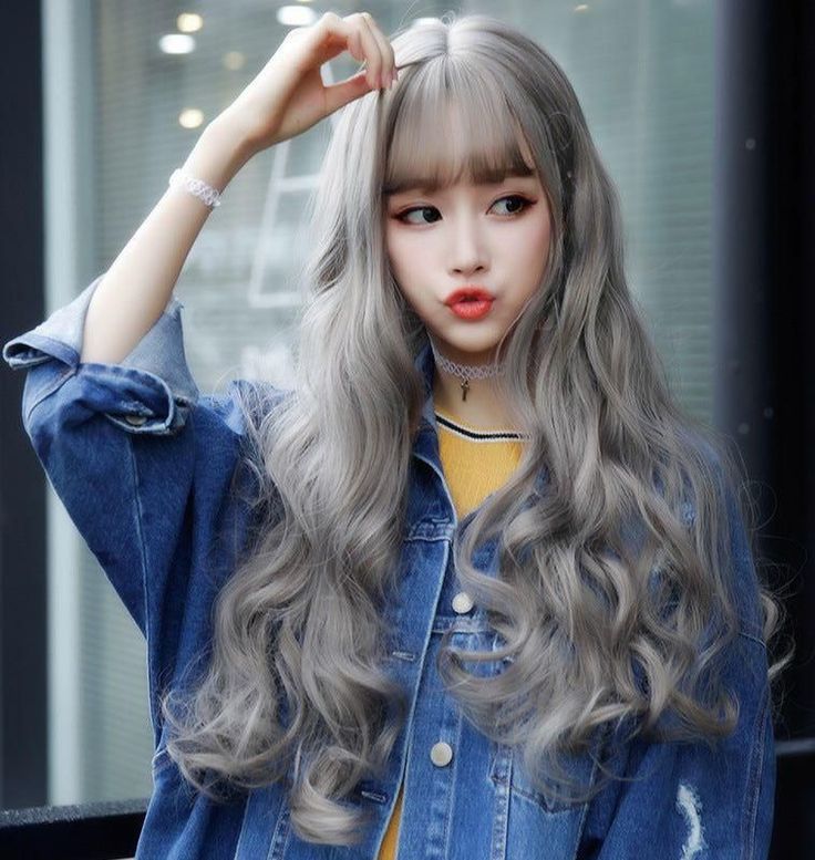 Woman with long wavy blonde hair wearing a denim jacket and choker