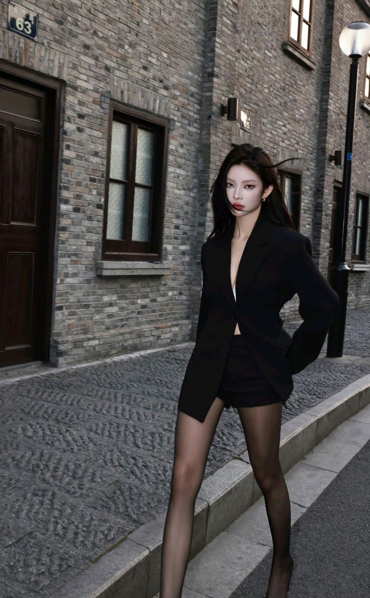 Woman in a black blazer and shorts with sheer stockings on a street