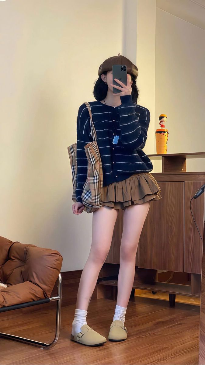 Person in a beret and striped cardigan taking a mirror selfie