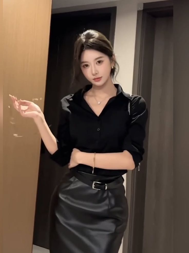 Woman in a black shirt and leather skirt posing indoors