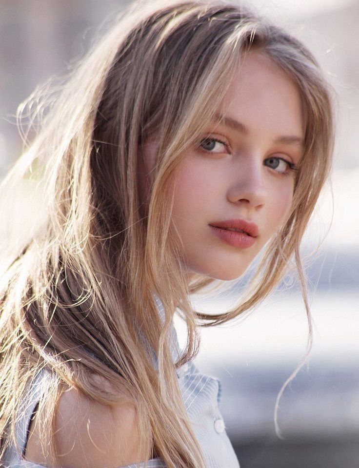 Young woman with long blonde hair and blue eyes in soft lighting