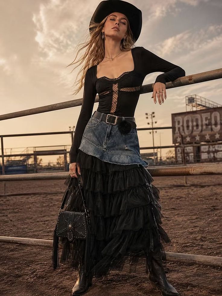 Woman in a cowboy hat and layered skirt posing in a rodeo arena at golden hour