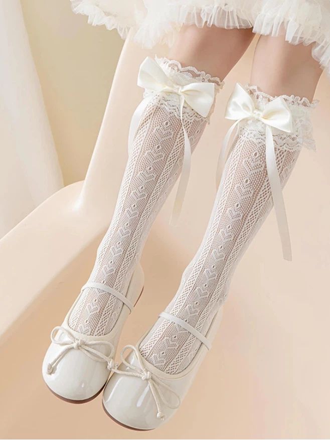 Legs wearing white lace knee-high socks with bows and white mary jane shoes