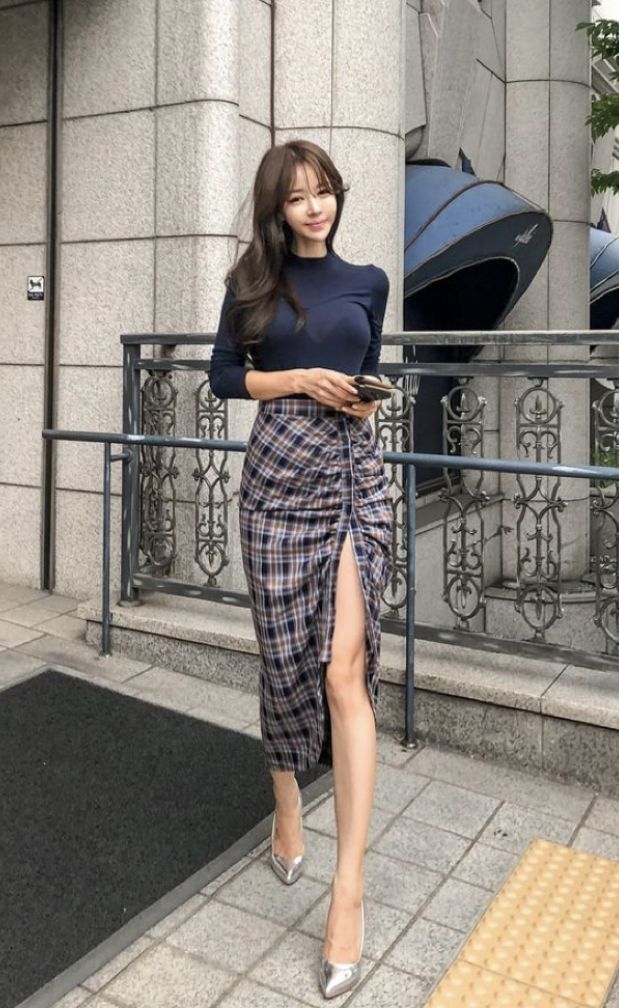 Woman with long hair wearing a plaid skirt with a high slit and silver heels