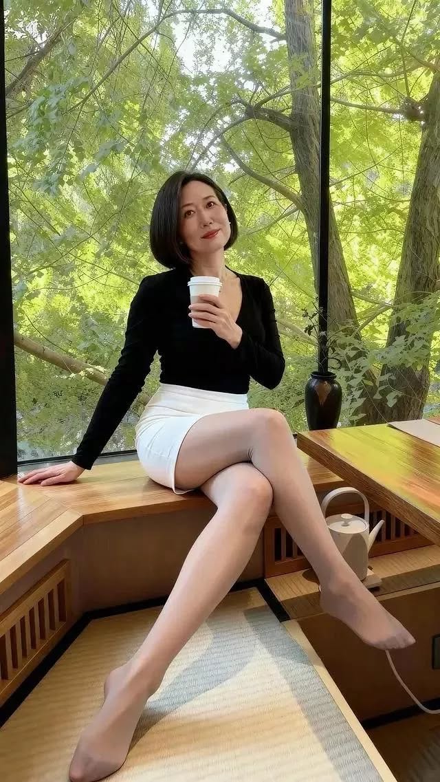 Woman with short hair in a white skirt and black top sitting indoors