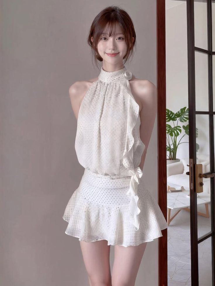 Woman in a white halter neck dress with ruffle details and polka dots indoors