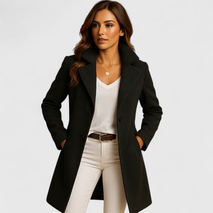 Woman in a black coat, white v-neck shirt, and white pants with a brown belt