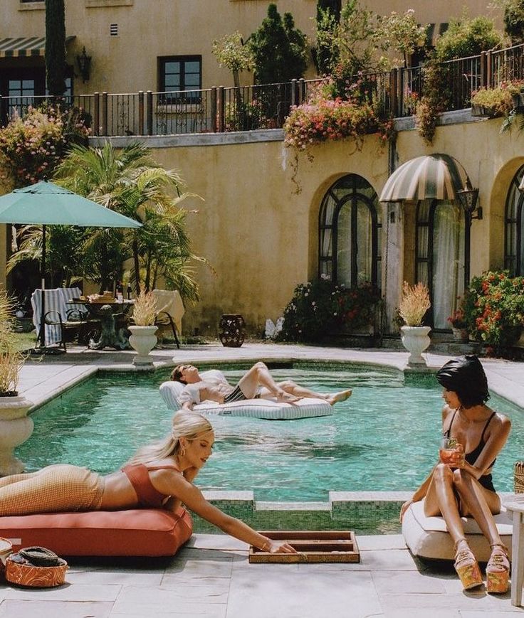 Three people relaxing by a swimming pool on a sunny day