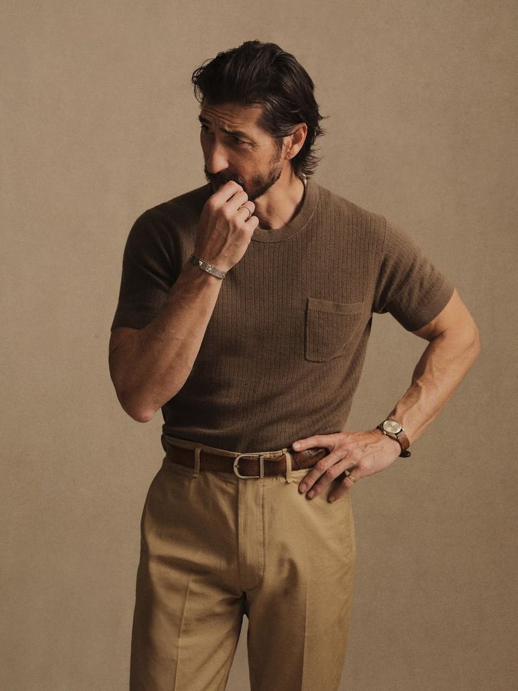 Man in a brown t-shirt and khaki pants with a short beard and long hair