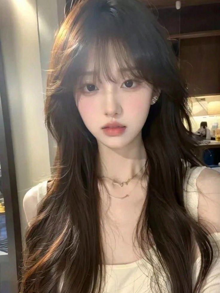 Woman with long dark hair and soft lighting indoors