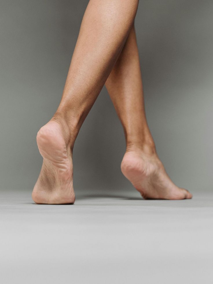 Bare legs and feet crossed against a grey background