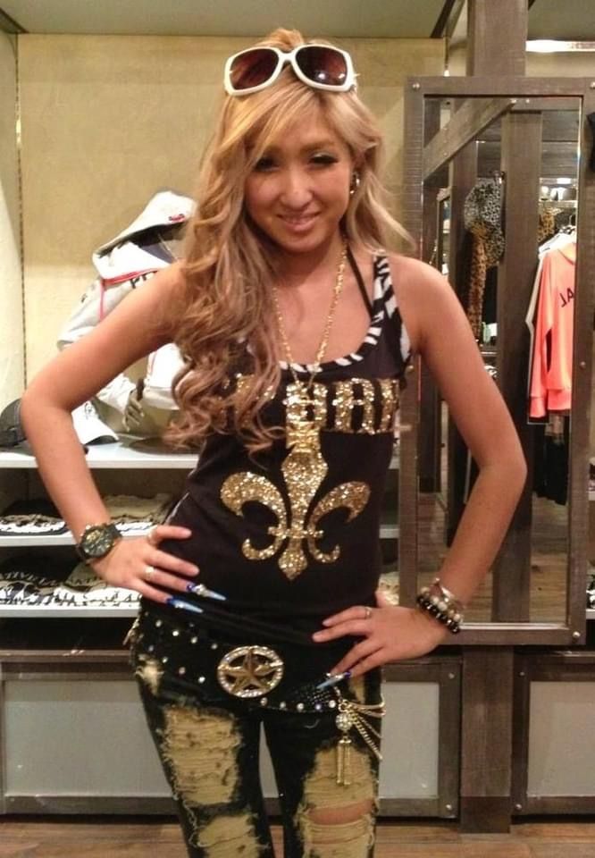 Woman with long blonde hair and sunglasses on her head, wearing a tank top and ripped jeans