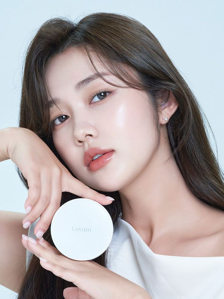 Woman with long hair and a white top holding a white compact product