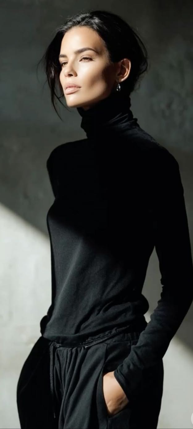Woman in a black turtleneck with dramatic lighting on her face