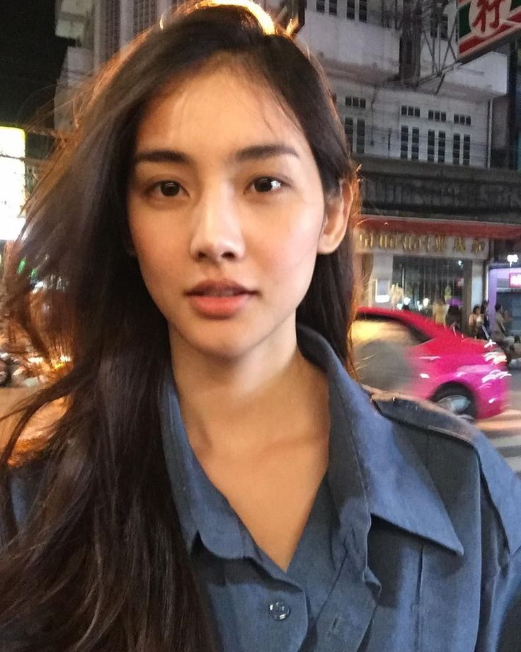 Woman with long dark hair wearing a blue shirt at night in a city
