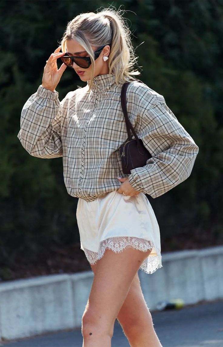 Woman in a plaid jacket and lace shorts outdoors on a sunny day