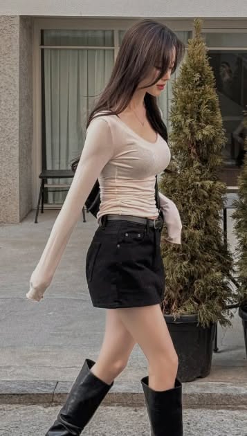 Woman with long hair wearing a black mini skirt and long sleeve top outdoors