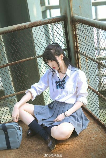 Woman in a school uniform sitting on a metal platform outdoors