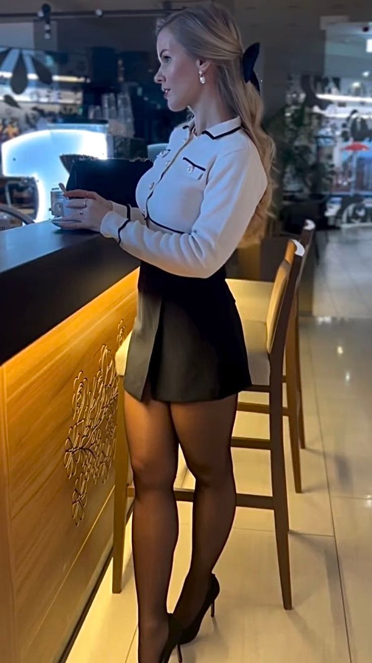 Woman with blonde hair in a mini skirt and high heels at a bar counter