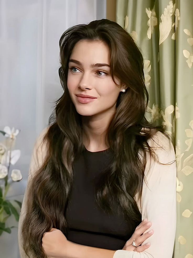 Woman with long wavy hair and heterochromia wearing a black top and beige cardigan