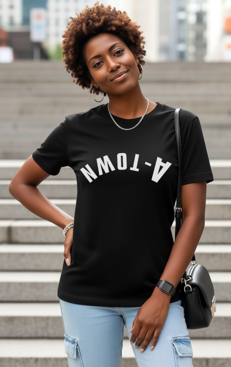 Woman with curly hair wearing a black t-shirt and light wash jeans outdoors