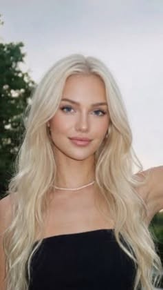 Woman with long blonde hair wearing a strapless top and pearl necklace outdoors