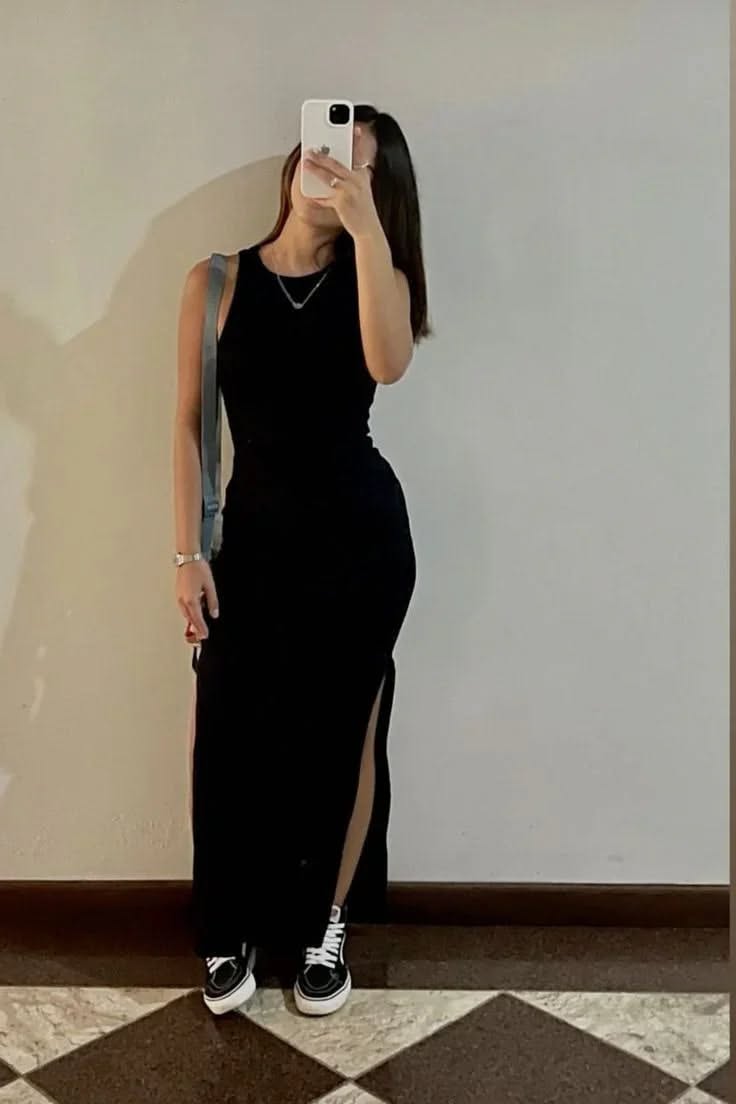 Woman in a black dress and sneakers taking a mirror selfie