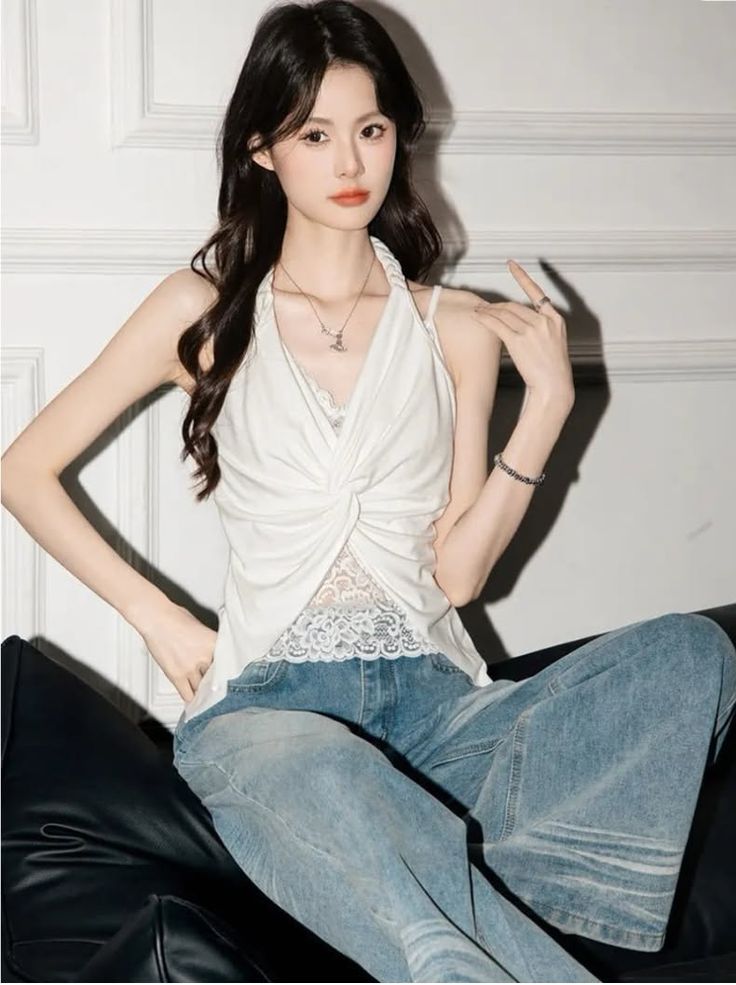 Woman with long dark hair wearing a white halter top and blue jeans indoors