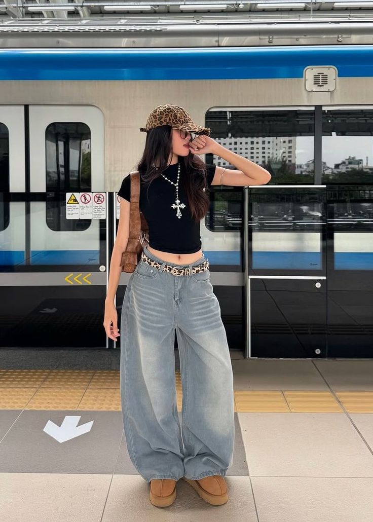Woman in a leopard print hat and wide leg jeans at a train station