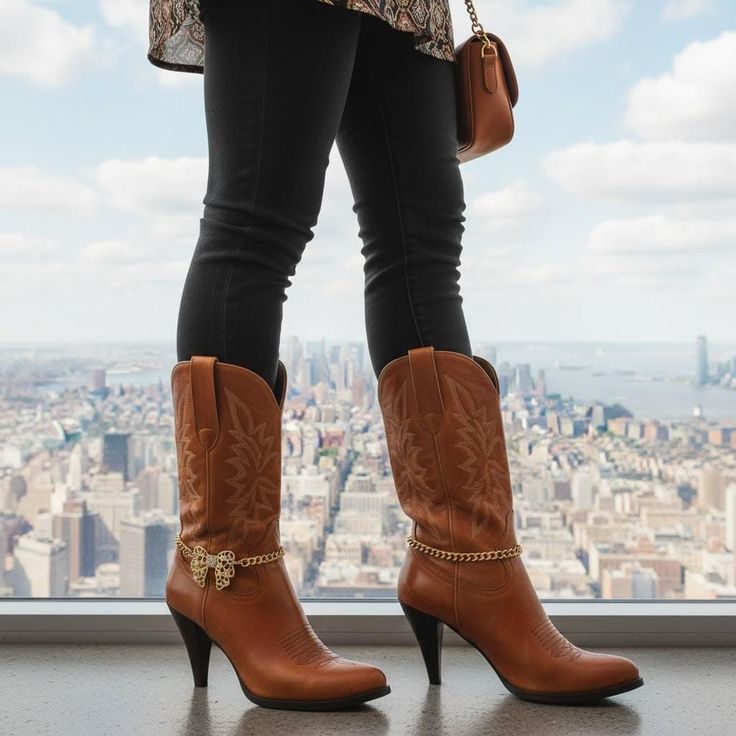 Person in cowboy boots and black jeans overlooking a cityscape