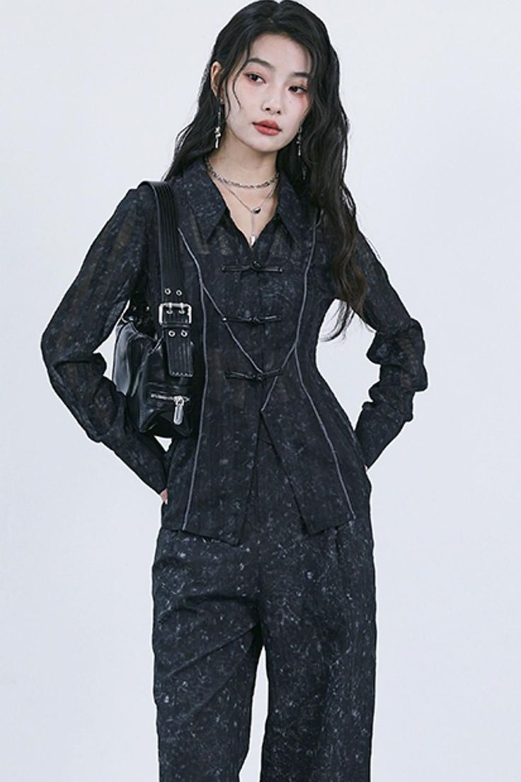 Woman with long dark hair wearing a dark patterned outfit and shoulder bag