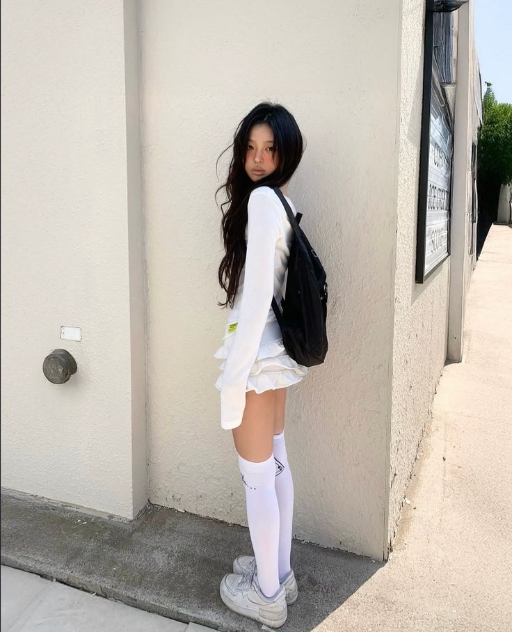 Young woman with long dark hair wearing a white top and mini skirt outdoors