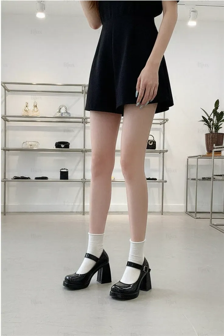 Woman in a black dress and mary jane shoes with white socks indoors