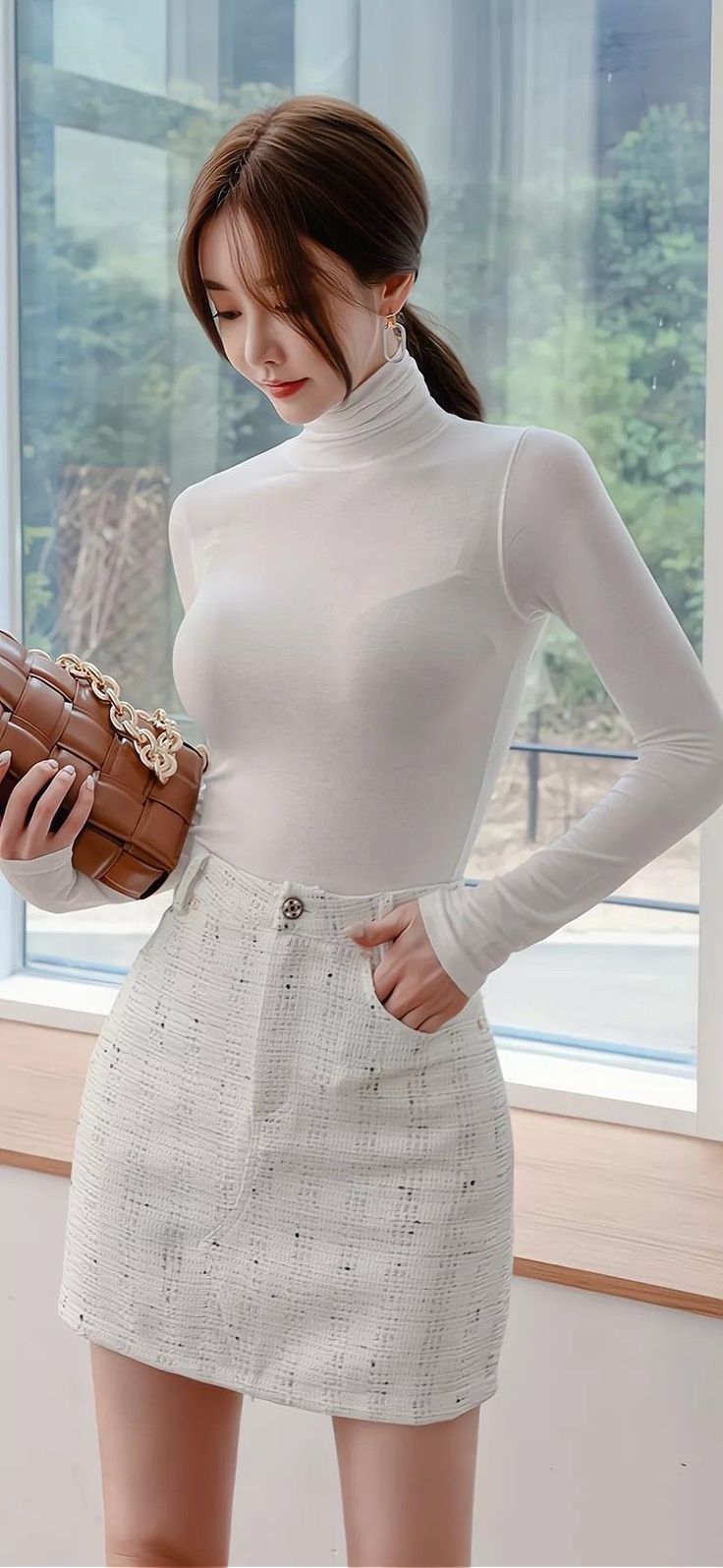 Woman in a white turtleneck and mini skirt holding a brown handbag indoors