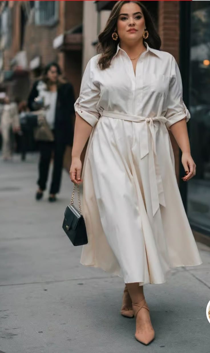 Woman in a cream midi dress and heels walking on a city street