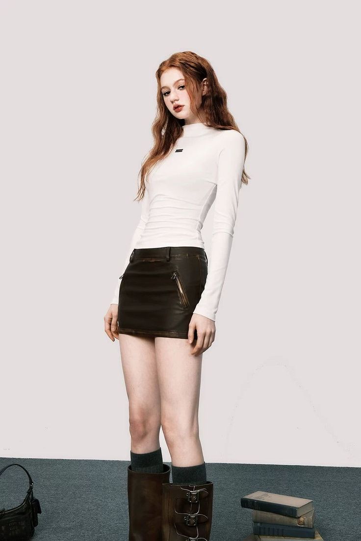 Woman with long red hair wearing a white top and mini skirt with boots