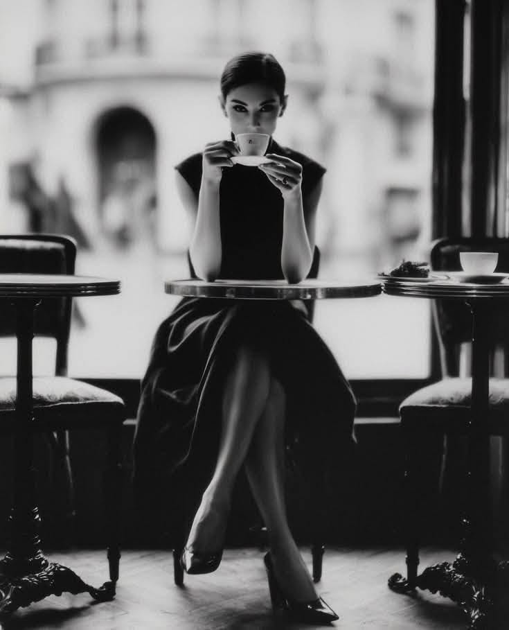 Woman in an elegant dress drinking coffee at a cafe table